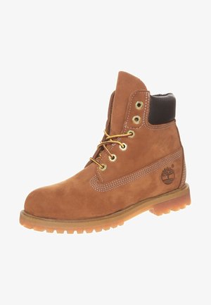 Botte de travail marron en cuir à lacets avec col rembourré noir, semelle robuste, œillets en métal et logo Timberland sur le côté.