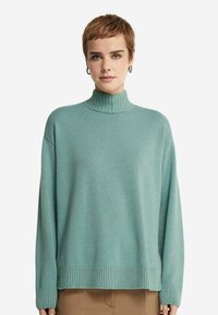 Jasnoniebieski sweter typu golf w miękkiej fakturze z lu�źnym krojem, prążkowanymi mankietami i dołem. Prosty wzór, średniej grubości dzianina.