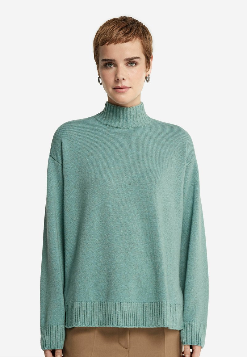 Jasnoniebieski sweter typu golf w miękkiej fakturze z luźnym krojem, prążkowanymi mankietami i dołem. Prosty wzór, średniej grubości dzianina.