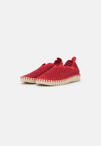 Scarpe slip-on rosse realizzate in materiale traspirante con design perforato; suola in gomma beige con motivo a zigzag e linguetta sul retro.