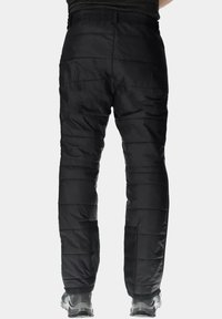 Zwarte geïsoleerde broek met een gewatteerde textuur, voorzien van een tailleband met trekkoord en tapered benen. Gedragen met grijze en zwarte wandelschoenen.