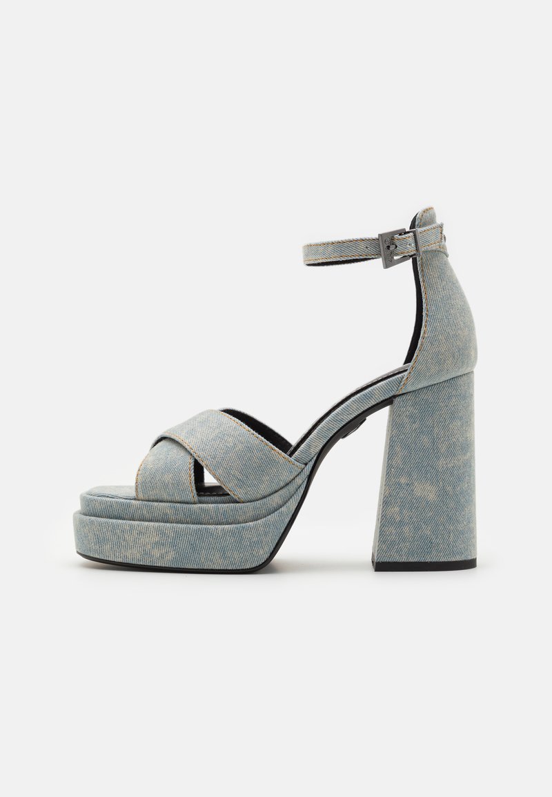 Denim platform szandál keresztpántos kialakítással, vastag magassarkúval és bokapánttal. Texturált világoskék farmer, kontrasztos varrással.