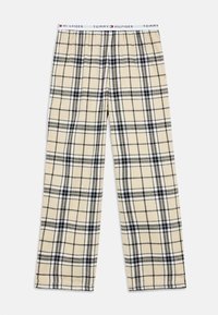 Beige and black plaid pajama pants with elastic waistband featuring Tommy Hilfiger branding and logo in red, white, and blue.
