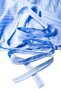 Tissu rayé bleu clair et blanc avec une longue cravate assortie étalée sur une surface plane.