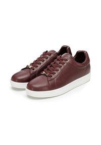 Sneaker in pelle bordeaux con texture liscia, suola in gomma bianca e occhielli in tonalità oro. Presenta una punta tonda e design con lacci.