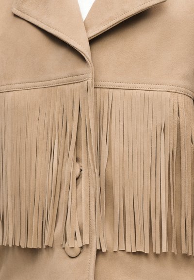 Beige suède jas met lange franjes over de borst en stofbedekte knopen aan de voorkant.
