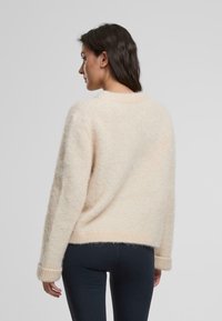 Helles Rosa, weicher Strickpullover mit langen Ärmeln und Rippenbündchen. Lockere Passform, runder Halsausschnitt und leicht verkürzter Saum.