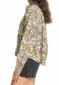 Långärmad skjorta i lätt material med en krämfärgad bas och ett multikulturellt blommönster och paisleymönster. Avslappnad passform, rundad nederkant.