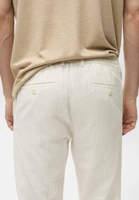 Jasnobeżowe spodnie w prążki z teksturowanej tkaniny, z dwoma tylnymi kieszeniami na guziki i elastycznym pasem.