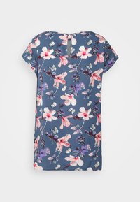 Camisa de manga curta floral em azul, com flores cor-de-rosa e roxas e borboletas. Decote redondo com um recorte em forma de olho na parte de trás.