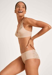 Beige bralette met kantafwerking en bijpassende hipster onderbroek. Soepele stof, zachte textuur en doorschijnende kanten details aan de zijkanten.
