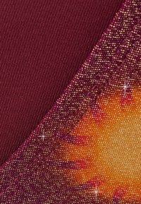 Bordowy materiał o fakturowanej powierzchni przechodzi w żywy, ciepły pomarańczowy wzór. Migoczące akcenty dodają głębi wzornictwu.