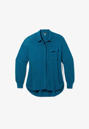 Teal langærmet skjorte med knaplukning lavet af tekstureret stof. Har en brystlomme og buet kant, med let glans i hele stoffet.