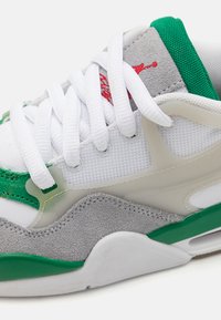 White sneakers featuring green and gray accents, mesh and suede materials, laces, and a translucent midsole with visible cushioning detail.