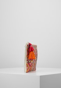 Pochette brodée multicolore avec des motifs géométriques, ornée de pompons rouges et orange, fermeture éclair blanche, et forme rectangulaire plate.