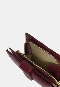 Burgunderfarbener Leder-Wallet mit einem Reißverschlussfach, mehreren Kartenfächern und einer glatten Textur. Goldene Hardware ergänzt das Design.