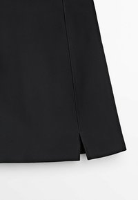 Black skirt with a smooth texture, featuring a side slit and clean lines. Made from woven fabric with a simple, modern design.