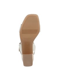 Sandal con tacco con parte superiore liscia in bianco sporco, design con punta aperta e suola rigida marrone. Presenta una larga cinghia alla caviglia e un tacco a blocco.