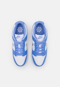 Nike sportcipők kék és fehér színkombinációval, bőr és hálós anyagból, perforált lábujjrésszel és kék fűzőkkel, valamint virággrafikával a talpbetéten.