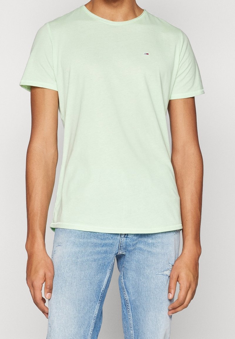 Světle mátově zelené tričko s kulatým výstřihem vyrobené z měkké látky. Krátké rukávy a rovný lem. Malý logo detail poblíž hrudi.