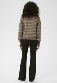 Un pull rayé marron avec des accents argentés, un col rond et des manches longues, accompagné d'un pantalon évasé noir, vu de l'arrière.
