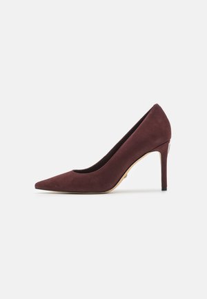 Décolleté in suede bordeaux con punta appuntita e texture liscia; presenta una silhouette elegante e un tacco a stiletto snodato.