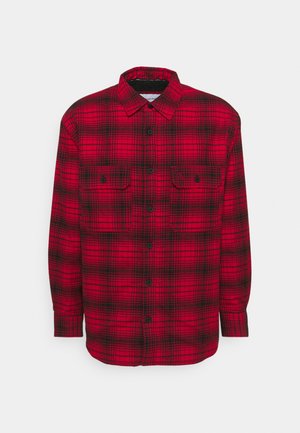 Camicia a quadri rossa e nera con bottoni, maniche lunghe, due tasche frontali e bottoni neri. Tessuto testurizzato con un classico motivo a scacchi.