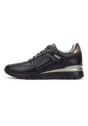 Zapatilla negra de cuero con acentos metálicos plateados, talón texturizado y costuras en contraste. Presenta una suela ligera y un diseño de cordones.