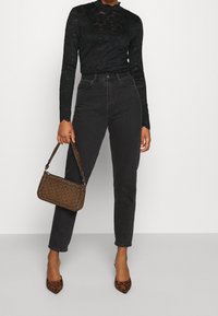 Sorte blondelange ærmede top, højtaljede sorte jeans, brun mønstret håndtaske og dyreprint spidse pumps.