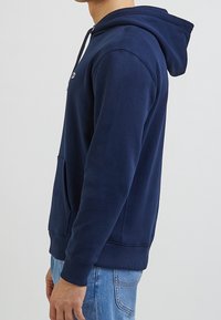 Felpa blu navy realizzata in tessuto misto cotone, con tasca a marsupio, cordoncino regolabile sulla cappuccio e polsini a coste.