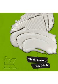 Tjock, vit krämig ansiktsmask virad på en lysande grön bakgrund, med texturerade penseldrag och en fet svart etikett med produktnamnet.