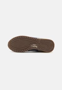Barna, textúrált gumitalp sneaker. Cikkcakkos mintázattal és középen nyomtatott logóval rendelkezik, tartós és alkalmi viseletre készült.