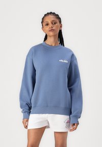 Sweatshirt bleu avec un col rond et des manches longues. Présente un logo blanc sur la poitrine et une finition texturée. Assorti avec un short blanc.