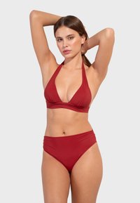 Rotes Bikini-Set mit einem Halterneck-Top mit tiefem V-Ausschnitt und hochgeschnittenen Bottoms mit gerafftem Stoff an den Seiten. Glatte Stofftextur.