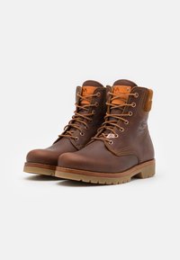 Brune lærankelsko med runde tæer, snørebåndsdesign, kontrasterende tan-accenter og en robust gummisål. Teksturerede finish på oversiden.