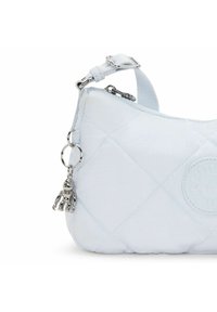 Ljusblå quiltad väska med rundad form, silverfärgade detaljer och en charm som liknar en robot. Mjuk textur med en sydd design.