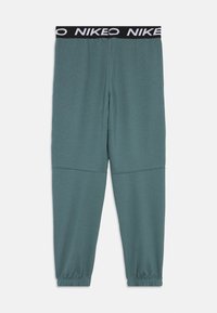 Teal Nike joggebukser med svart elastisk midje som har hvit "NIKE"-tekst, smale ben og elastiske mansjetter.