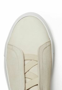 Beige sneaker with a smooth leather upper, elastic laces, and a white rubber sole. Rounded toe and minimalistic design. Soft texture.