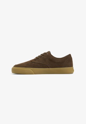 Brown suede sneakers with a low-profile design, rounded toe, and rubber sole. Features six eyelets for laces and a textured surface.