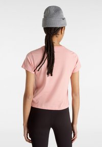 Korte roze katoenen t-shirt met korte mouwen en een ronde halslijn, gedragen met zwarte leggings en een grijze gebreide muts.