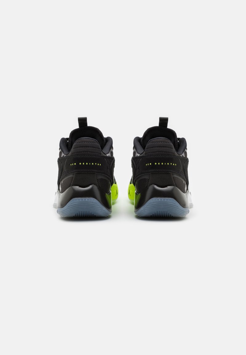 Zapatillas deportivas negras con acabado suave, que presentan detalles en verde neón, tela texturizada y una suela de goma gris. Incluyen tiradores traseros.