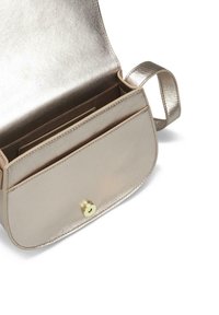 Bolso de mano metálico dorado con una textura suave, diseño curvado y un bolsillo frontal. Presenta un cierre a presión y una correa delgada.