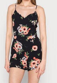 Czarny kombinezon w kwiaty na ramiączkach, z różowo-białymi wzorami kwiatowymi, dekoltem w serek i dopasowanym w pasie.