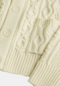 Cardigan lavorato a maglia crema con motivo a trecce, polsini a coste e chiusure con bottoni. Realizzato in un tessuto misto lana testurizzato.