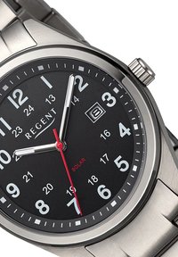Montre analogique avec un bracelet en acier inoxydable, cadran noir, chiffres blancs, aiguille des secondes rouge et fenêtre de date affichant la date. Alimentée par énergie solaire.