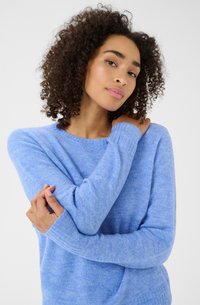 Light blue sweater with a soft texture, ribbed cuffs, and a classic crew neckline, worn by a model with curly hair.