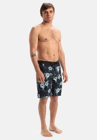 Μαύρο μαγιό βερμούδα με λουλουδάτο σχέδιο που περιλαμβάνει ανοιχτό μπλε και λευκά λουλούδια, κατασκευασμένο από ελαφρύ υλικό, μήκους μέχρι το γόνατο.