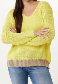 Yellow knitted sweater with a V-neck, loose fit, and beige ribbed hem and cuffs. The texture is open-knit, creating a lightweight look.