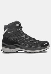 Bota de senderismo negra con parte superior de malla, acentos de gamuza, suela de goma gris y ojales metálicos. Diseñada para durabilidad y tracción.
