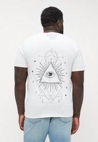 Weißes Baumwoll-T-Shirt mit schwarzem geometrischem und Augendesign auf der Rückseite, kurzen Ärmeln und einem normalen Rundhalsausschnitt.